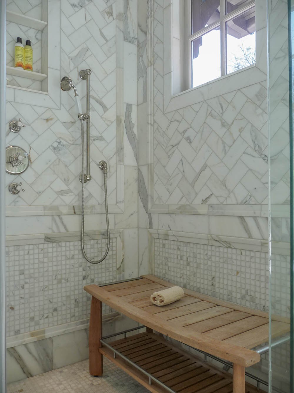 Fantastic bathroom shower features calcutta gold marble herringbone tiles as