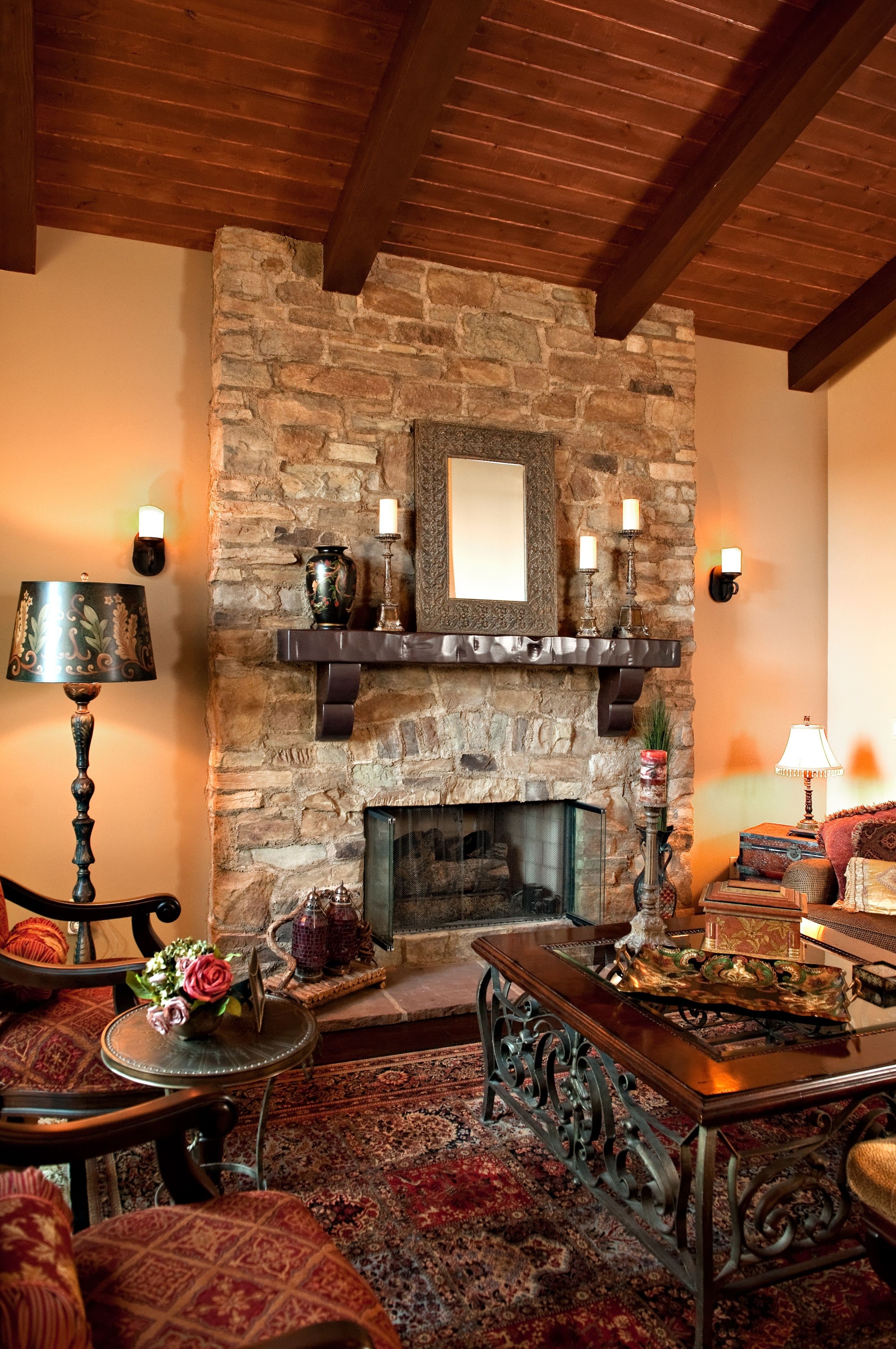 Mediterranean living room with dark wood ceilings stone fireplace and