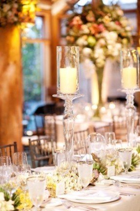 Tall glass hurricanes onto of glass candlesticks and beautiful floral