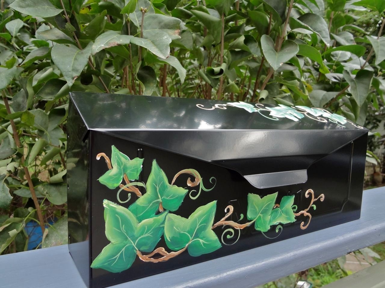 Hand painted mailbox with green ivy vines on a black