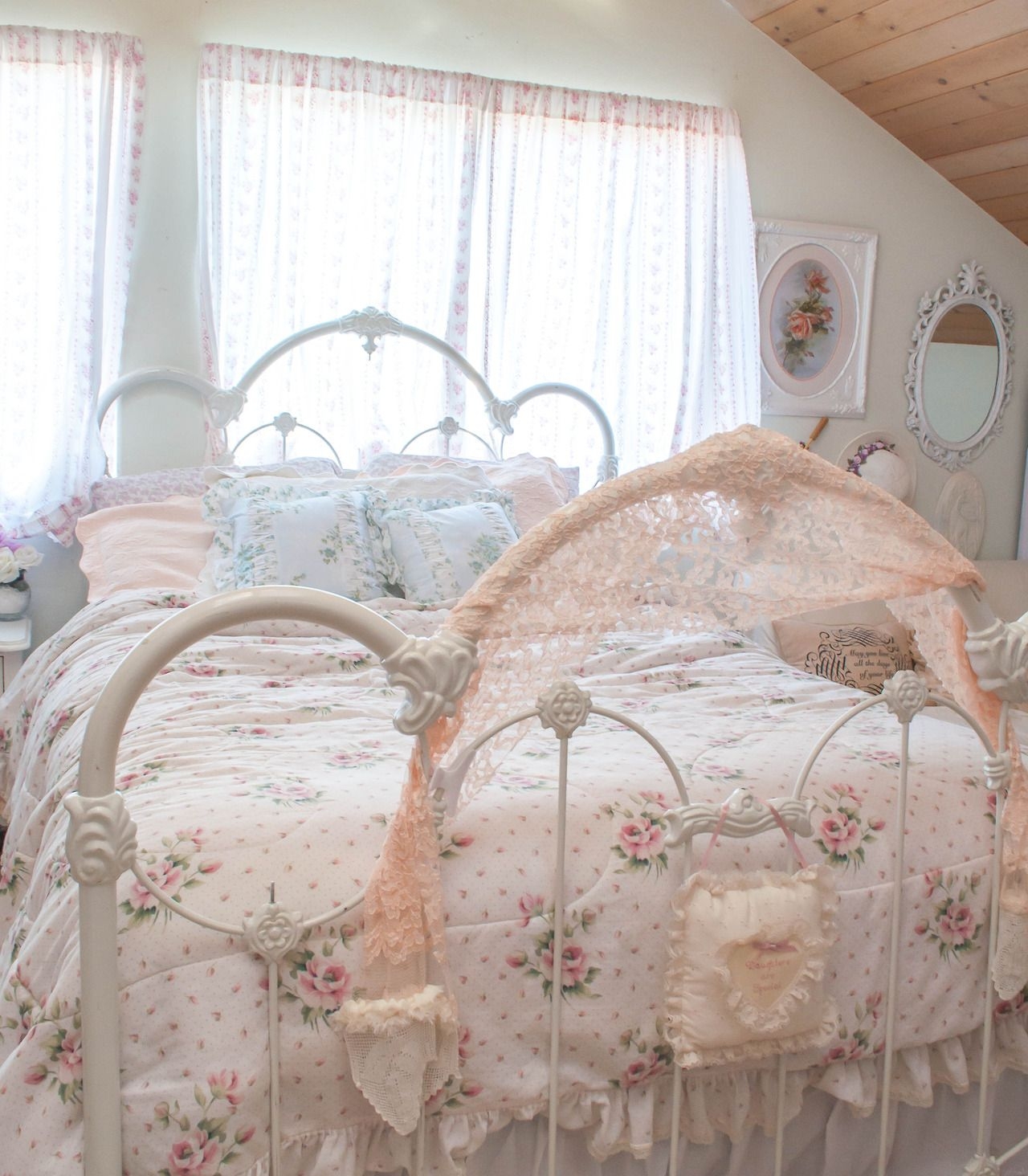 Iron bed frame including pink flowery bed sheets and white