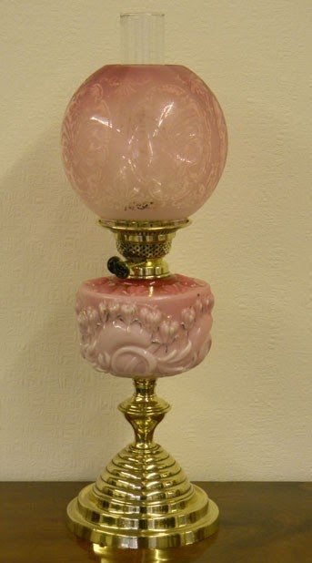 Antique victorian oil lamp having an original cranberry pink shade