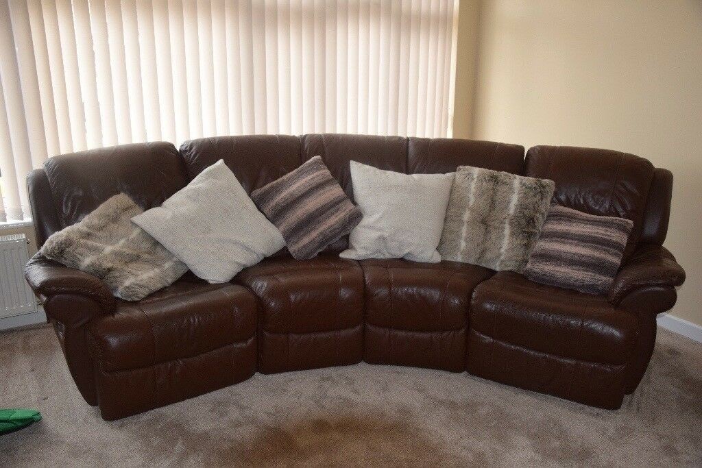 A curved brown leather sofa with recliners at either end