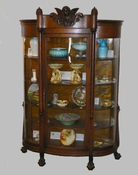 Antique oak china curio cabinet with carved cherub in the