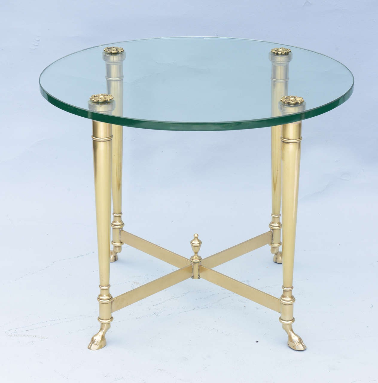 Polished brass end table with glass top on hoffed feet